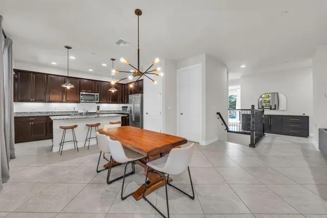 a dining room filled a chandelier and kitchen view