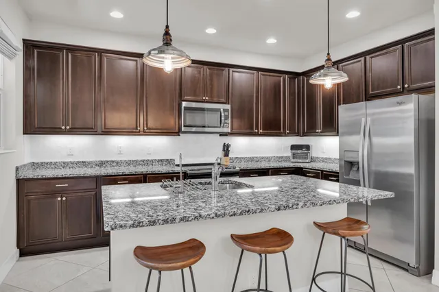 a kitchen with stainless steel appliances granite countertop a stove a refrigerator a sink with a dining table and chairs