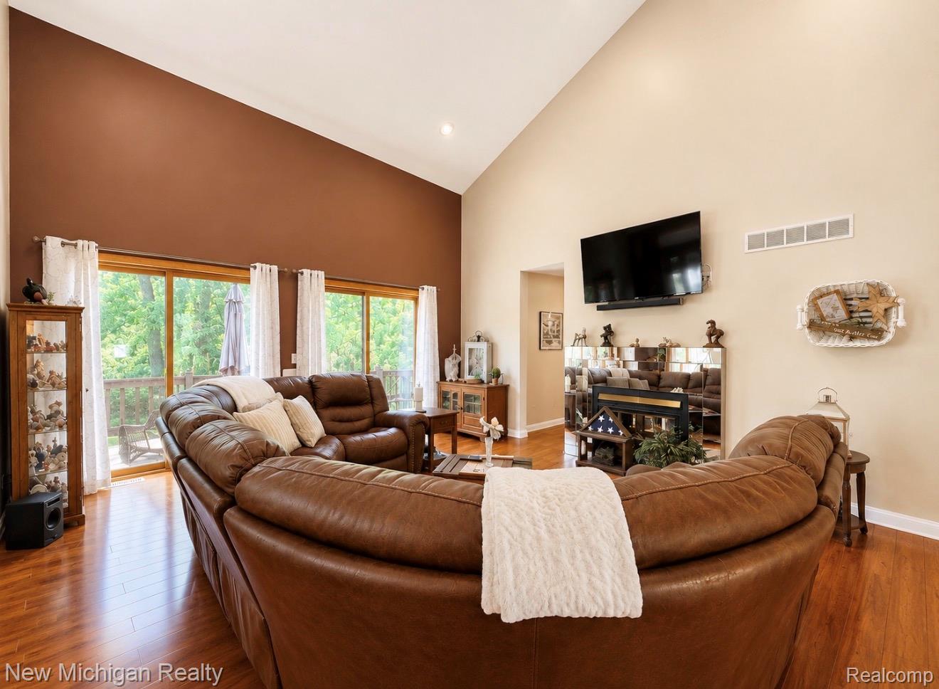7156 East River Road Flushing, MI 48433 - Photo 6 of 35 Living area featuring vaulted ceilings, wood-finish flooring, recessed lighting, and expansive sliding glass doors leading to an outdoor space