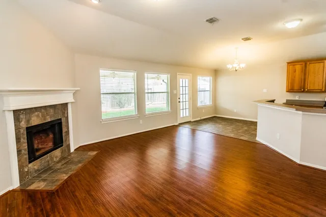 a view of an empty room with window and wooden floor