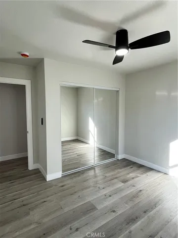 an empty room with wooden floor cabinet and windows