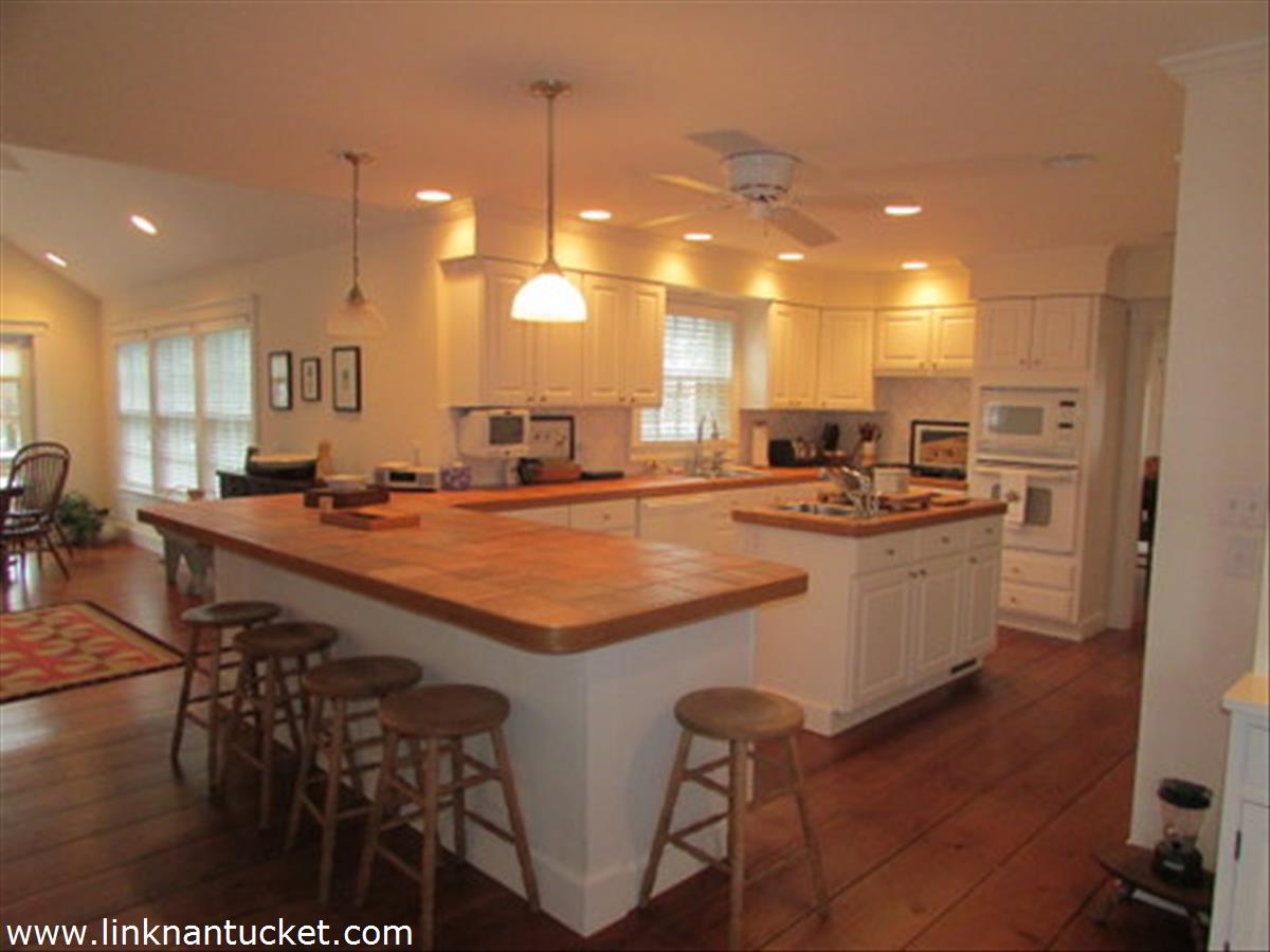73 Fairgrounds Road Nantucket, MA 02554 - Photo 4 of 15 a dining hall with stainless steel appliances kitchen island granite countertop a sink a stove a dining table and chairs