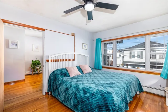 a bedroom with a bed and a large window with wooden floor