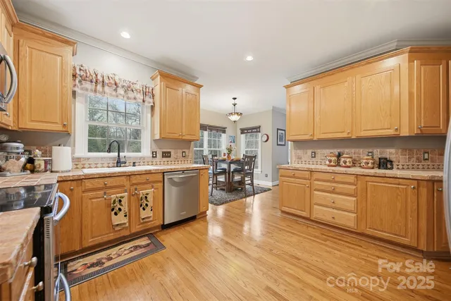 a large kitchen with stainless steel appliances granite countertop a stove a sink dishwasher and cabinets with wooden floor