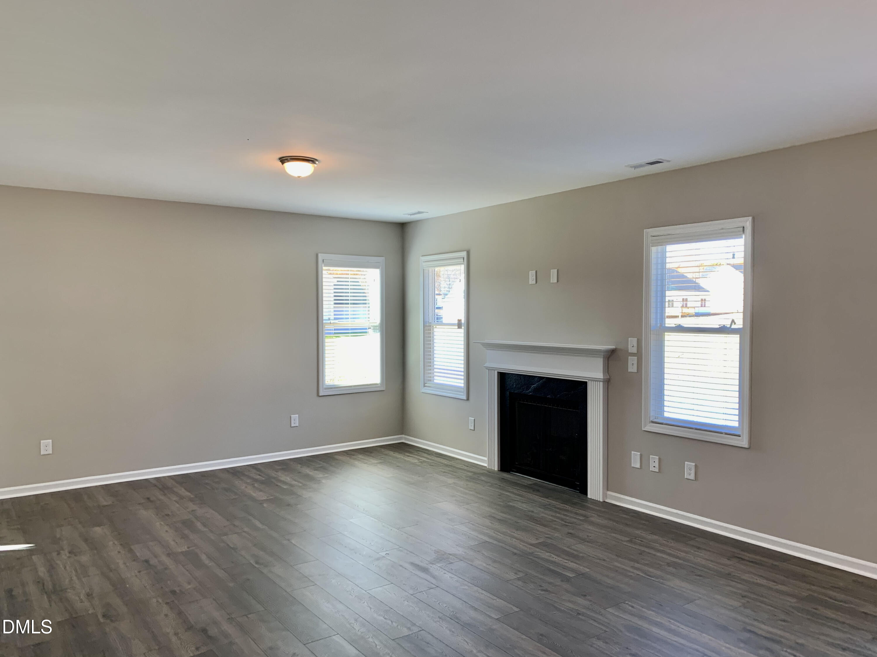 48 Weathervane Dr. Zebulon, NC 27597 - Photo 3 of 24 an empty room with wooden floor fireplace and windows