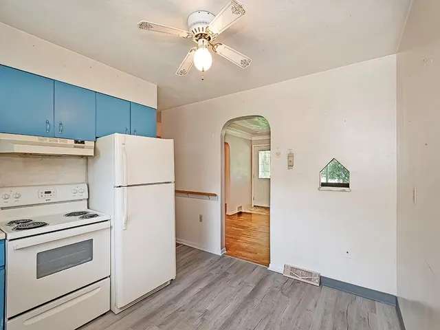 a kitchen with a refrigerator a stove and white cabinets