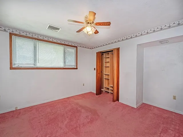 an empty room with closet and a ceiling fan