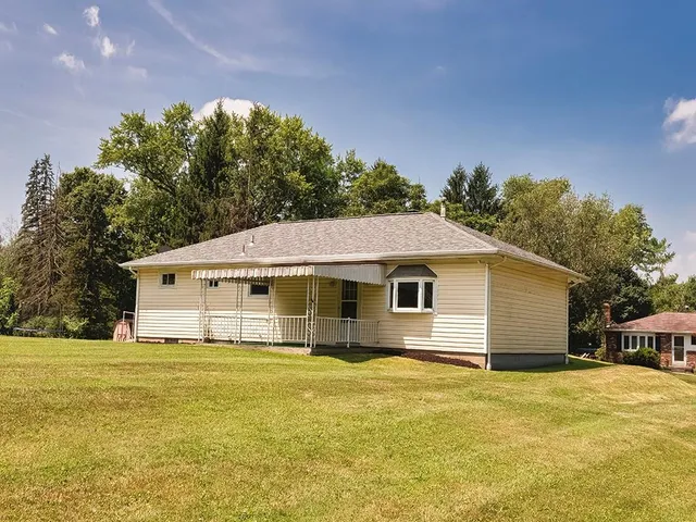 a front view of house with yard and trees in the background