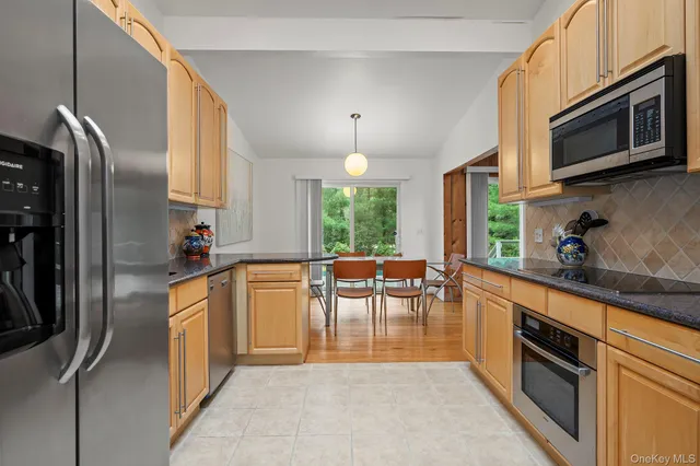 a kitchen with stainless steel appliances granite countertop a refrigerator a stove a sink a dining table and chairs