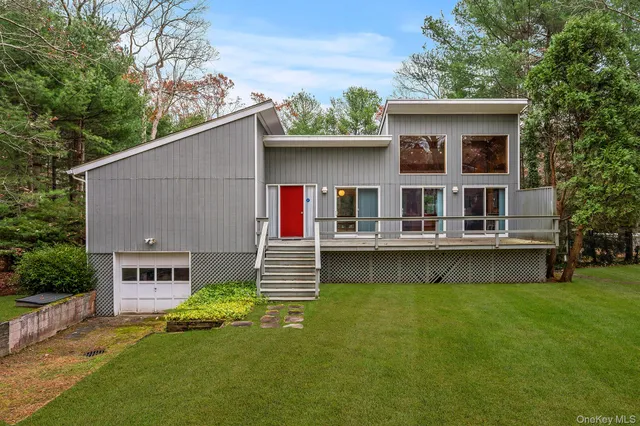 a front view of house with yard and trees in the background