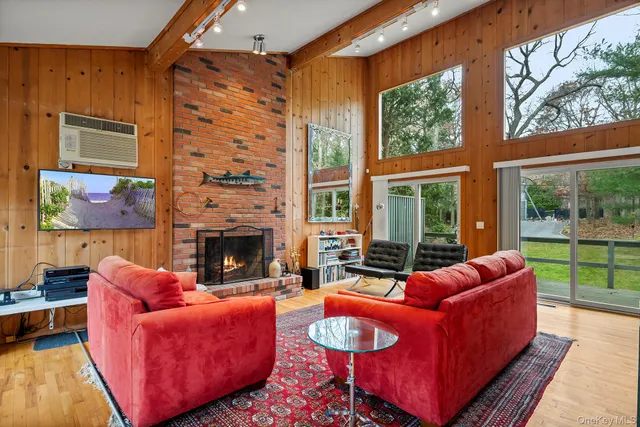 a living room with furniture a fireplace and floor to ceiling windows