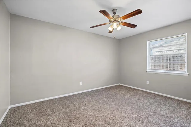 an empty room with window and ceiling fan