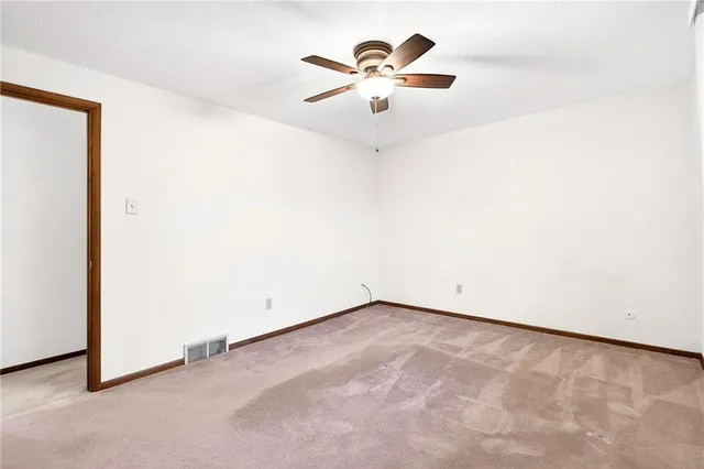 an empty room with a chandelier fan and a window