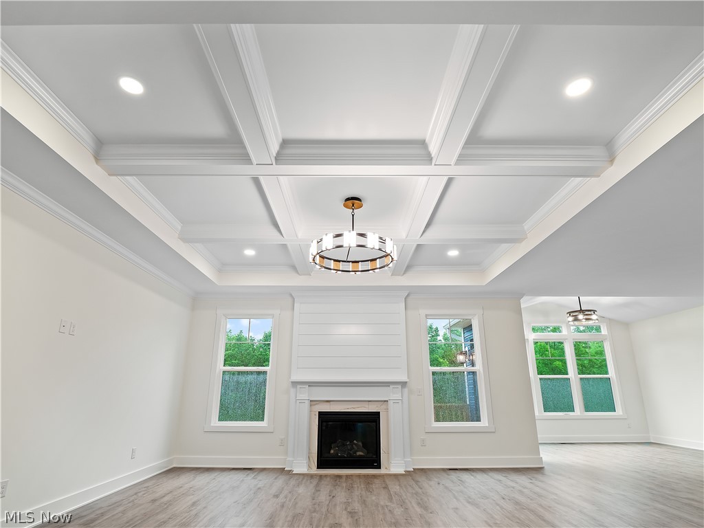 32 Brookside Lane North Ridgeville, OH 44039 - Photo 21 of 50 Unfurnished living room featuring light wood-style flooring, beamed ceiling, crown molding, a premium fireplace, and recessed lighting