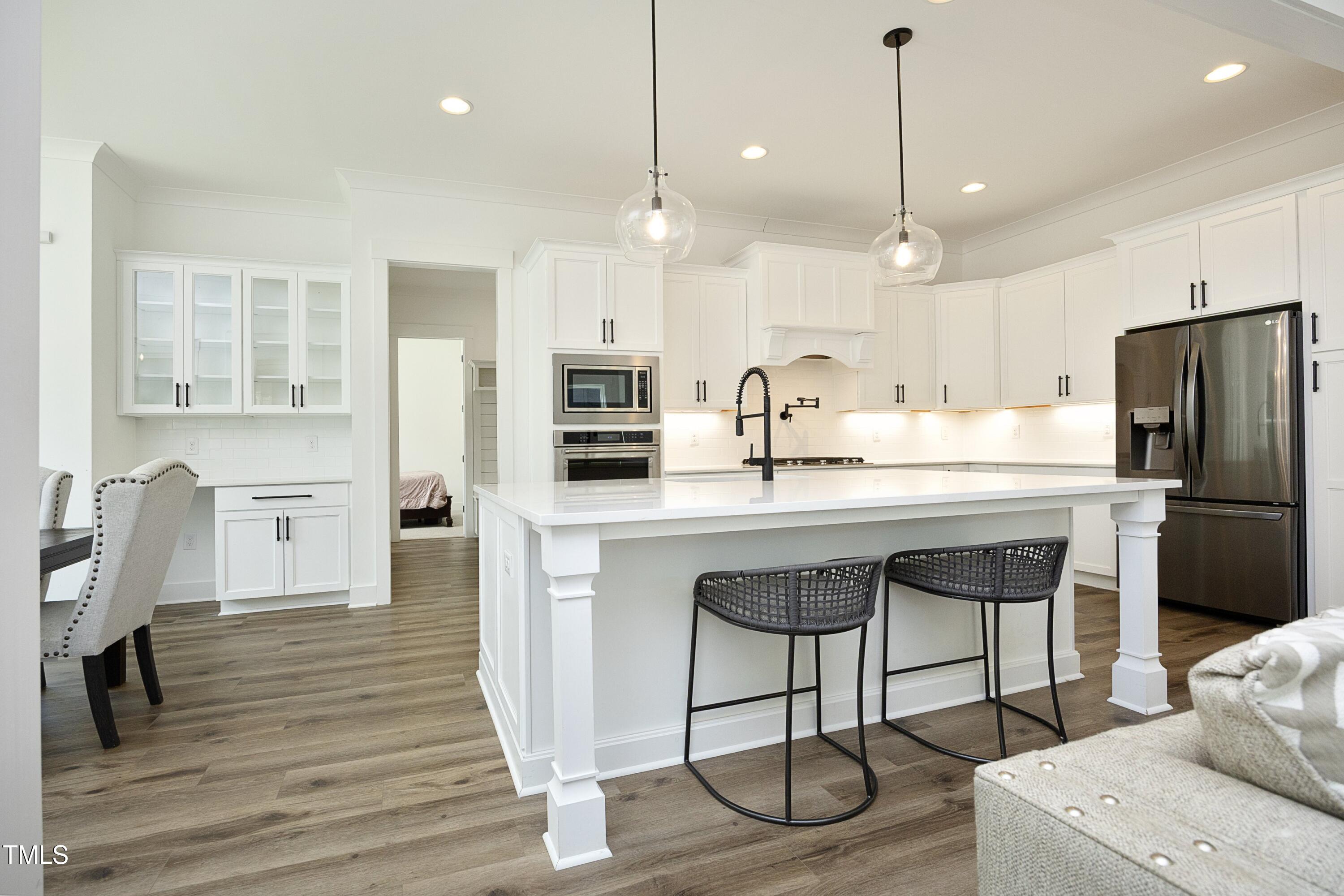 1145 Duke Farm Drive Wake Forest, NC 27587 - Photo 5 of 37 a kitchen with stainless steel appliances granite countertop a sink a stove a refrigerator and island with wooden floor