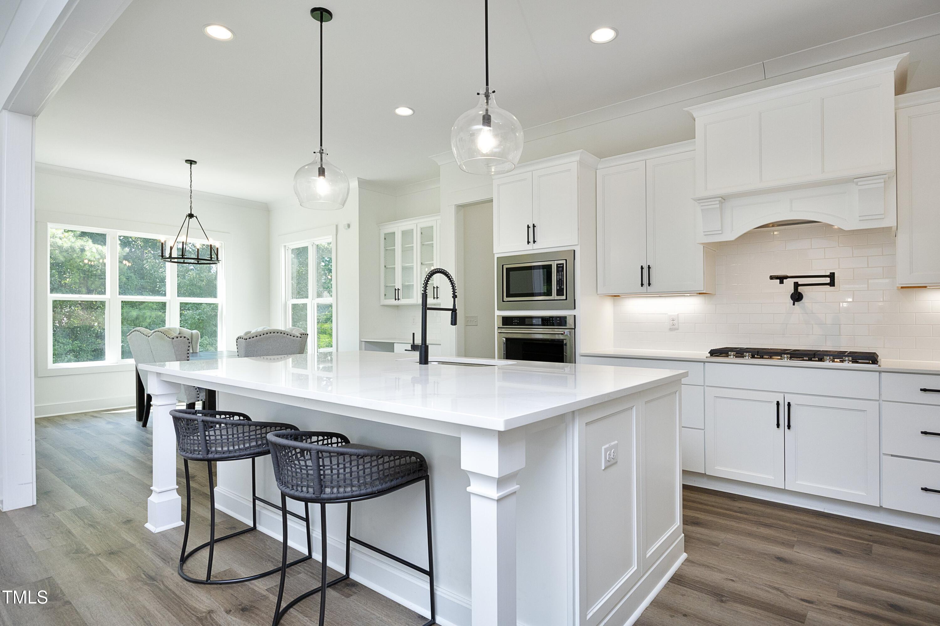 1145 Duke Farm Drive Wake Forest, NC 27587 - Photo 6 of 37 a kitchen with stainless steel appliances kitchen island a table chairs in it and wooden floors