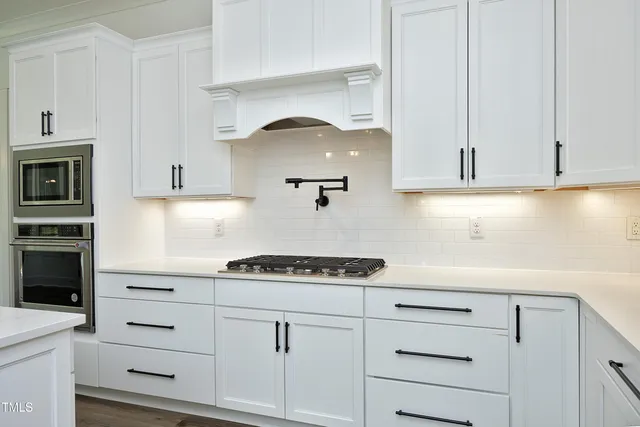 a kitchen with stainless steel appliances granite countertop a sink a stove a refrigerator and island with wooden floor