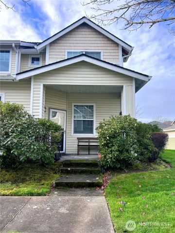 a view of a house with a yard plants and large tree