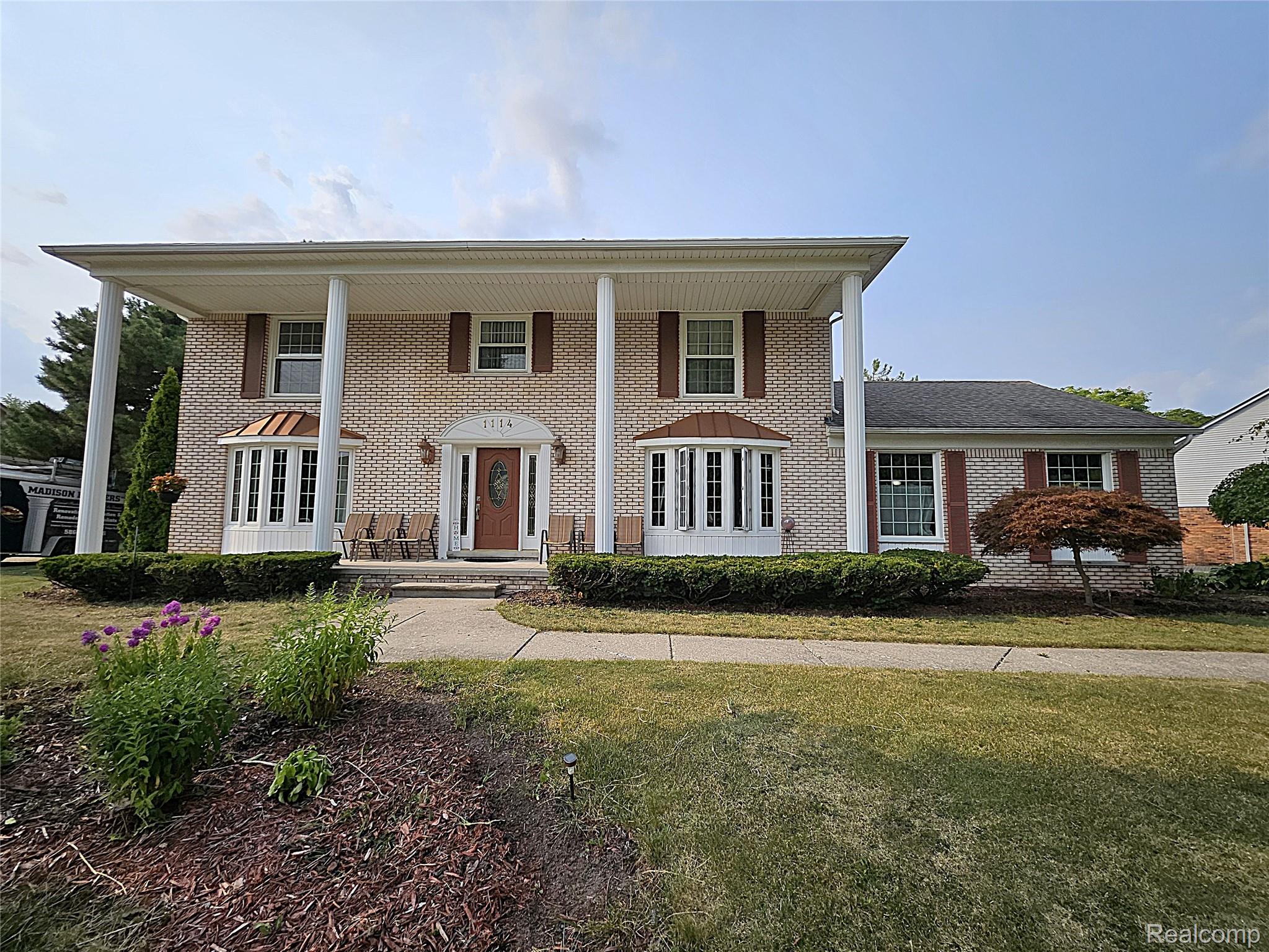 1114 Chaffer Drive Rochester, MI 48306 - Photo 2 of 50 Elegant brick Colonial featuring a symmetrical facade with white columned portico, arched entryway, and dual French doors