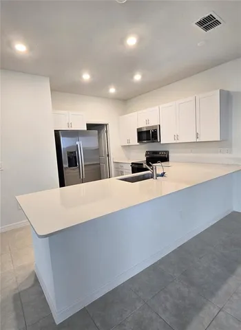 a large white kitchen with kitchen island a sink a stove a microwave and cabinets