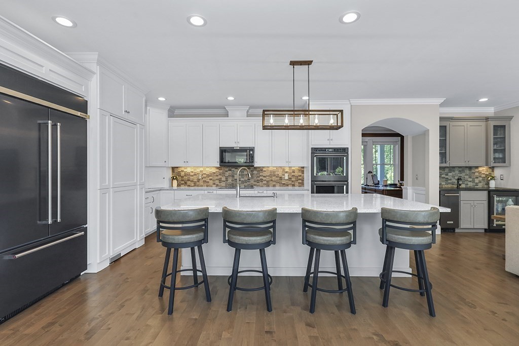 23 September Drive Franklin, MA 02038 - Photo 19 of 42 a kitchen with stainless steel appliances kitchen island granite countertop a refrigerator a stove a dining table and chairs with wooden floor