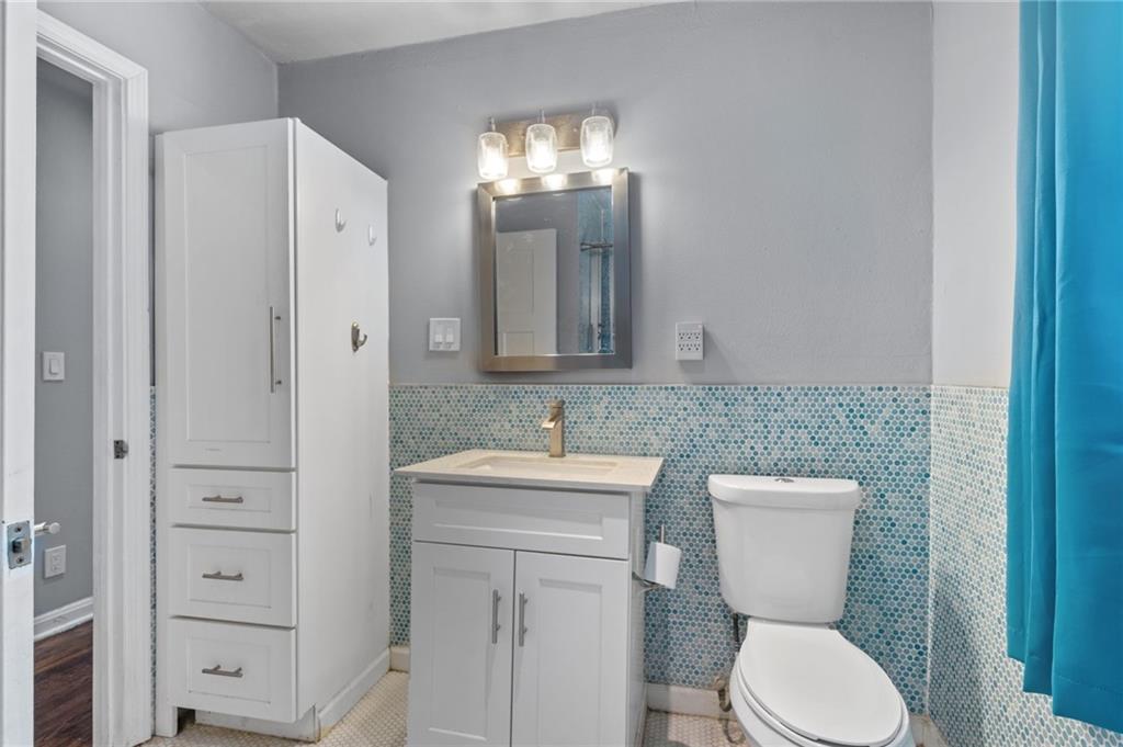 2105 Fortview Road Austin, TX 78704 - Photo 28 of 37 A compact bathroom offers stylish blue mosaic tile wainscoting and convenient built-in storage.