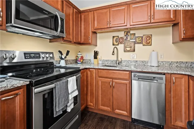 a kitchen with stainless steel appliances granite countertop a stove top oven a sink dishwasher and cabinets with wooden floor