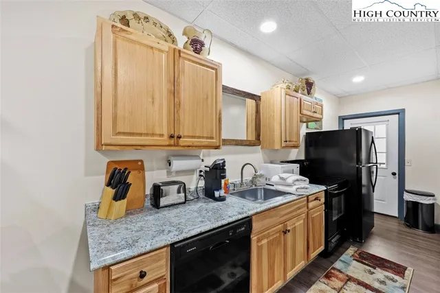 a kitchen with granite countertop stainless steel appliances a sink stove refrigerator and cabinets