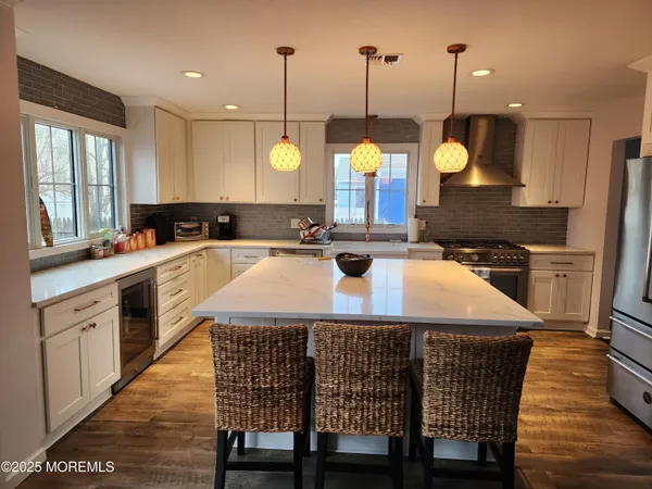 a kitchen with stainless steel appliances granite countertop a stove a sink dishwasher a microwave oven a dining table and chairs with wooden floor