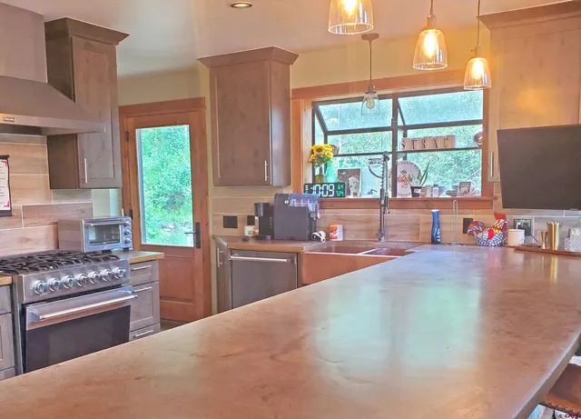 a kitchen with stainless steel appliances a sink cabinets and a large window