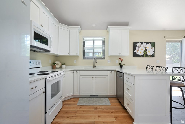 865 South 325 West Orem, UT 84058 - Photo 11 of 38 Modern kitchen featuring white cabinetry, light-toned countertops, a built-in microwave, a flat-top stove, and wood-finish flooring