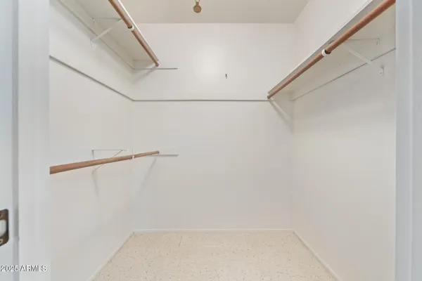 an empty room with a chandelier fan and windows