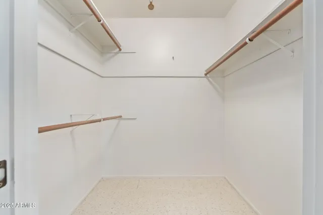 an empty room with a chandelier fan and windows