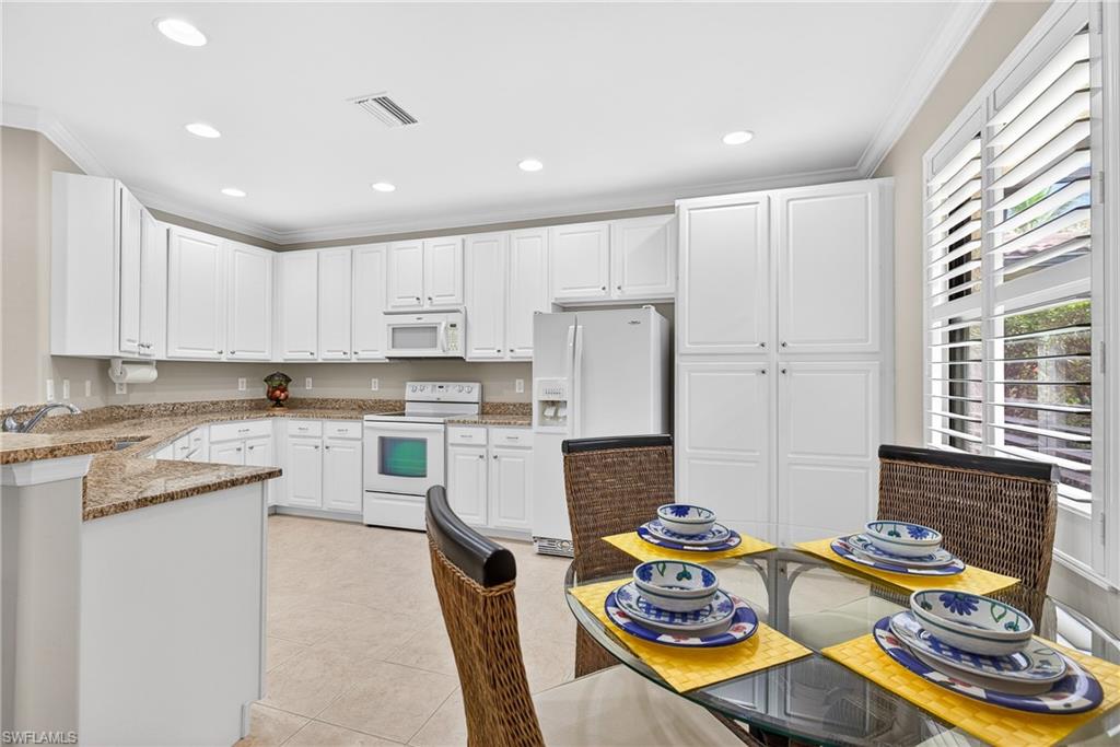 1248 Manado Drive Naples, FL 34113 - Photo 11 of 45 a kitchen with stainless steel appliances granite countertop a sink and white cabinets