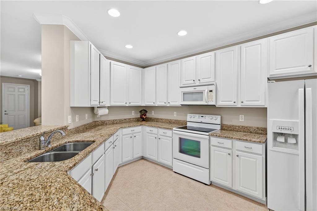 1248 Manado Drive Naples, FL 34113 - Photo 14 of 45 a kitchen with granite countertop white cabinets sink and stainless steel appliances