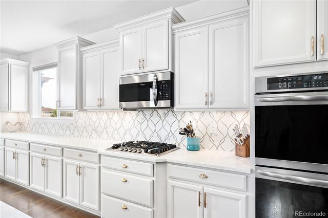 a kitchen with granite countertop white cabinets and black appliances