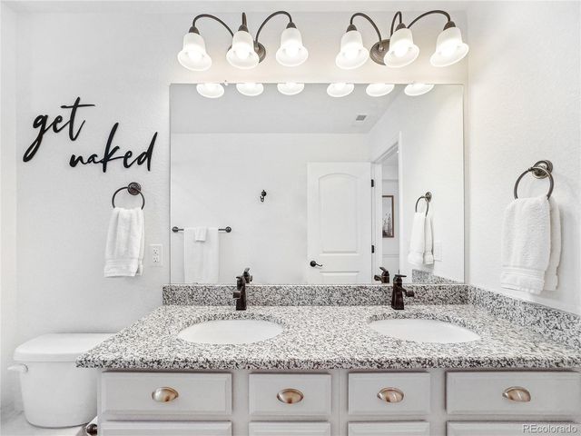 a bathroom with a granite countertop double vanity and a mirror