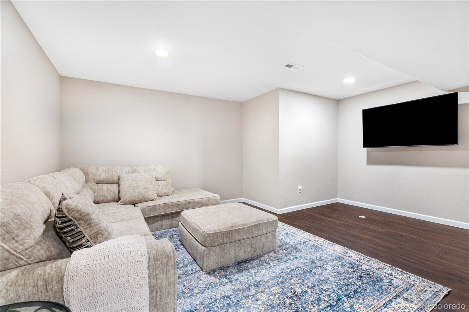 16391 Buffalo Run Drive Commerce City, CO 80022 - Photo 33 of 49 a living room with a couch and a flat screen tv