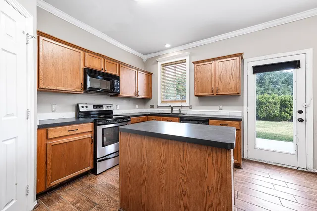 a kitchen with stainless steel appliances granite countertop a stove a sink and a microwave