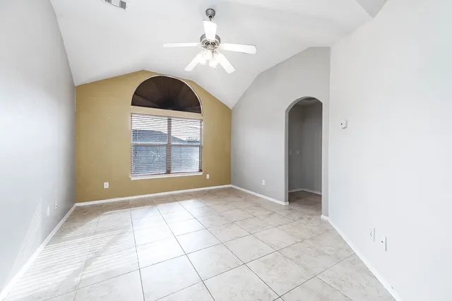 an empty room with windows and ceiling fan