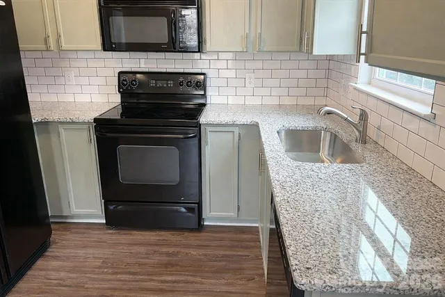 a kitchen with granite countertop cabinets appliances and wooden floor