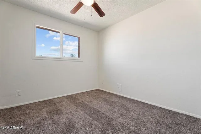 an empty room with a window and a ceiling fan