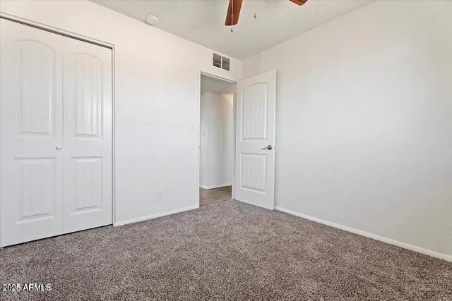 an empty room with closet and a chandelier fan