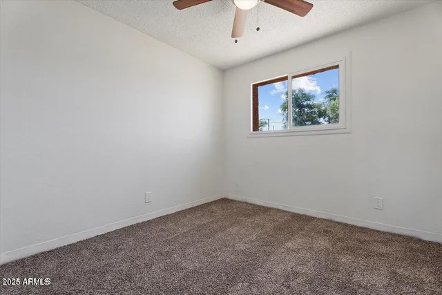 an empty room with a window and a ceiling fan