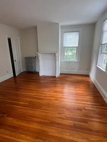 a view of an empty room with window and wooden floor