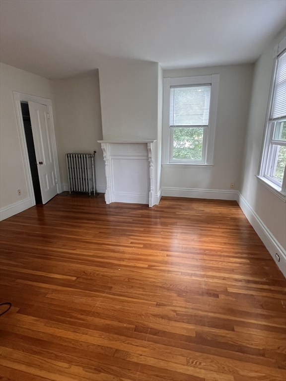 a view of an empty room with window and wooden floor