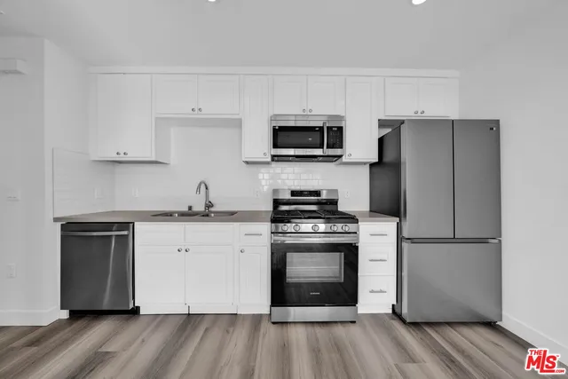 a kitchen with cabinets stainless steel appliances and a wooden floor
