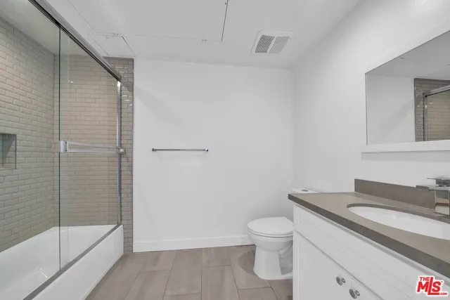 a bathroom with a granite countertop toilet a sink and a shower