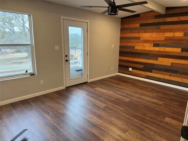 a view of an empty room with wooden floor and a window