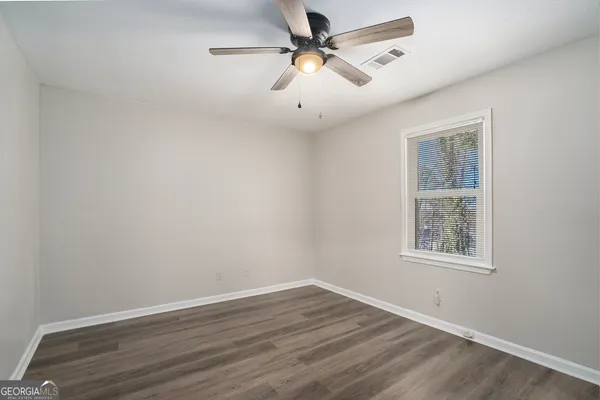 a view of an empty room with a window and wooden floor